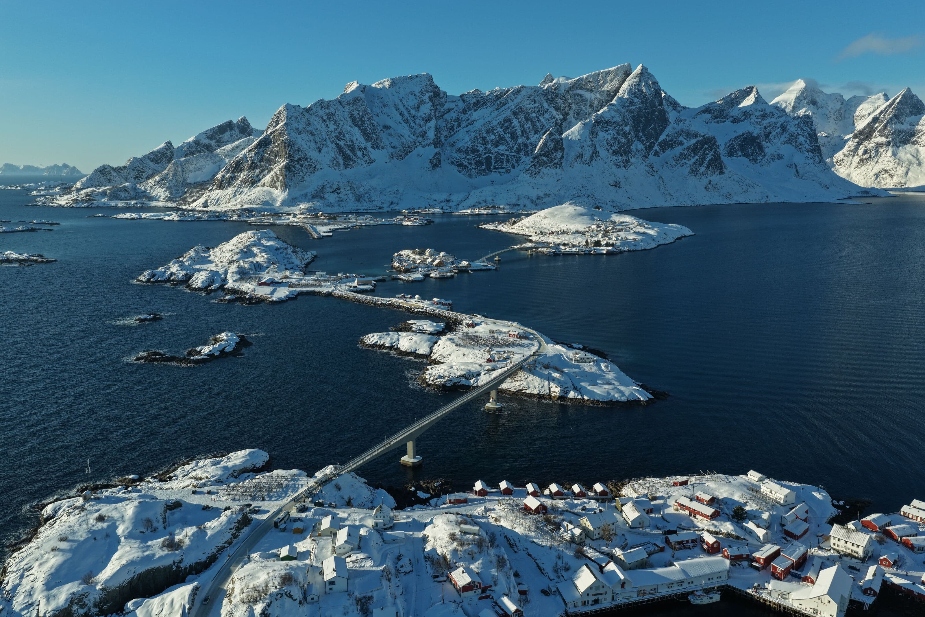 Vista aérea del pueblo de Reine, en las islas Lofoten (Noruega), con su puente y montañas nevadas