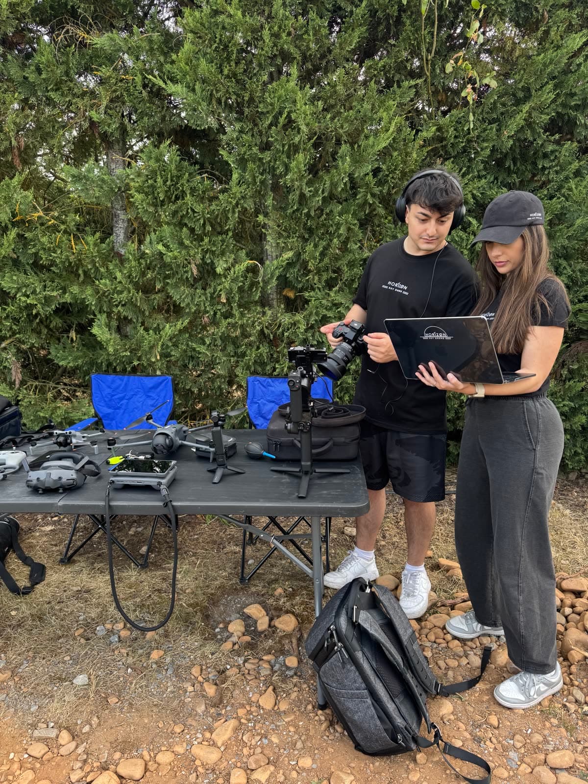 Dos miembros del equipo de Horizon Sky Drone revisando material de rodaje en un portátil, junto a la mesa con el equipo de dron y cámara