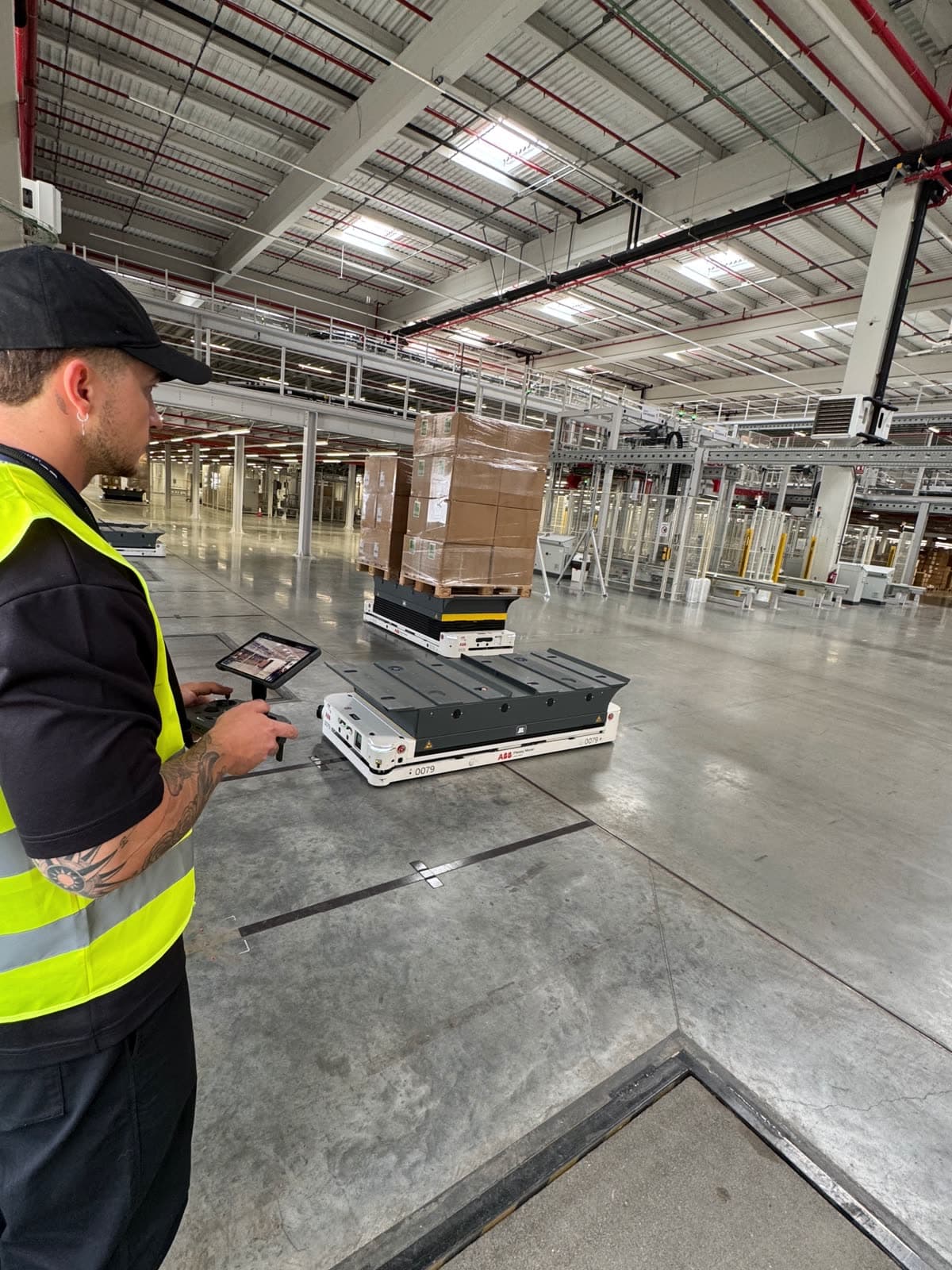 Piloto de Horizon Sky Drone con chaleco reflectante controlando un dron en un almacén logístico automatizado, junto a un robot AGV